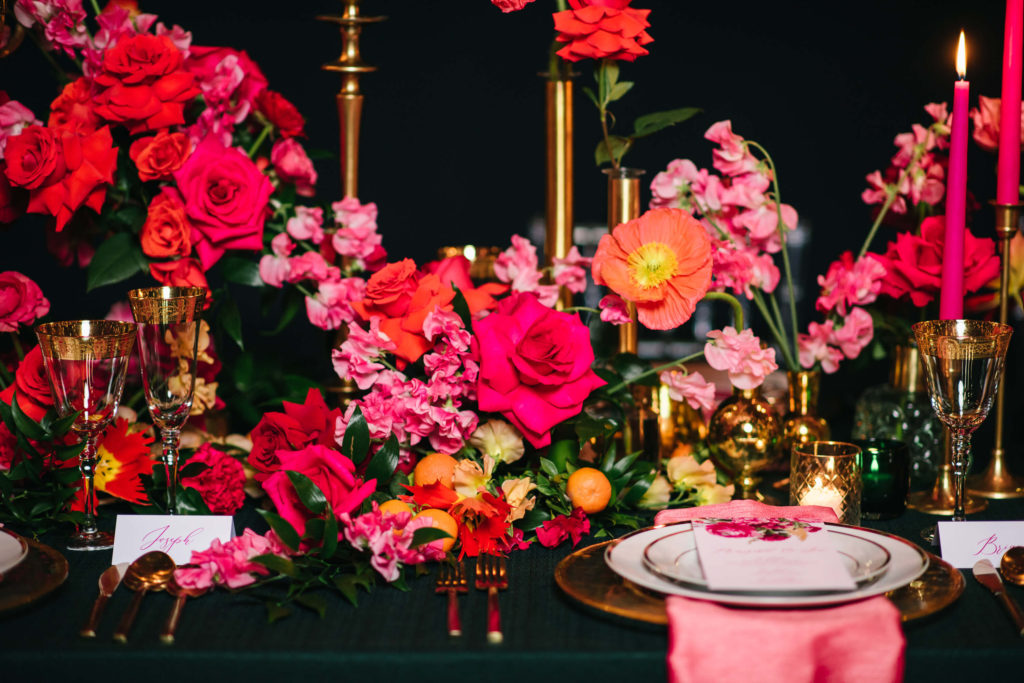 pink and orange wedding table decor with gold accents and lit pink candles